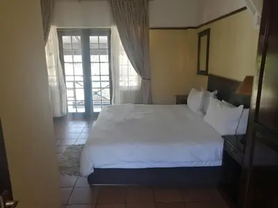 a bedroom with a large white bed and a window at The Woodsman Bed and Breakfast in Sabie