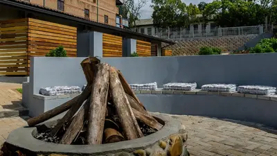 a fire pit with logs in front of a wall at The Woodsman Bed and Breakfast in Sabie