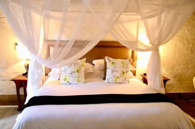a bedroom with a canopy bed with white curtains at Entabeni Mountain Lodges in Golders Green
