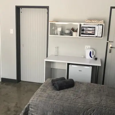 a bedroom with a bed and a desk and a microwave at The Red Chimney in Pretoria