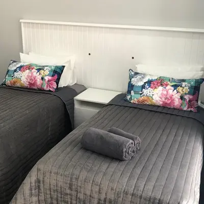 two twin beds in a room with a towel on the bed at The Red Chimney in Pretoria