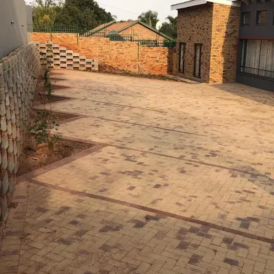 a brick driveway with a fence and a brick wall at The Red Chimney in Pretoria