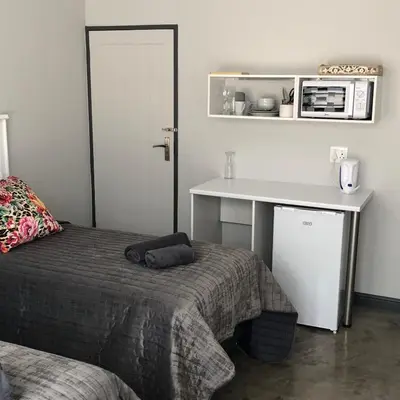 a bedroom with a bed and a table and a desk at The Red Chimney in Pretoria
