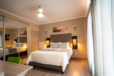 a hotel room with a bed and a mirror at Meadowbrook Guesthouse in Pretoria