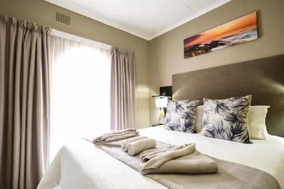 a bedroom with a large white bed with a window at Meadowbrook Guesthouse in Pretoria