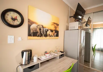 a kitchen with a refrigerator and a clock on the wall at Meadowbrook Guesthouse in Pretoria