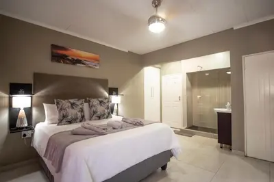 a bedroom with a large bed and a bathroom at Meadowbrook Guesthouse in Pretoria