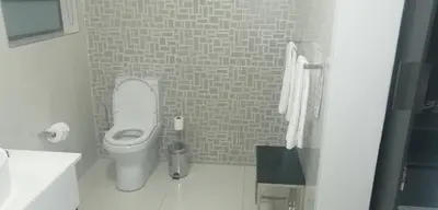 a white bathroom with a toilet and a sink at Prisatt Boutique Hotel in Onverwacht
