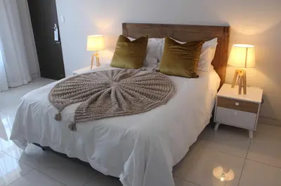 a bedroom with a large white bed with two lamps at Prisatt Boutique Hotel in Onverwacht