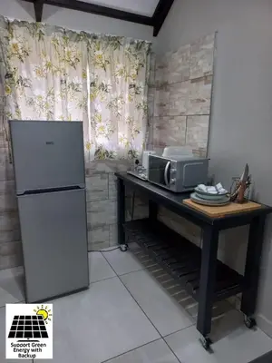 a kitchen with a refrigerator and a table with a microwave at SnL 12 Dwergarend in Malelane