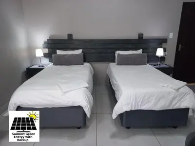 two beds in a hotel room with white sheets and pillows at SnL 12 Dwergarend in Malelane