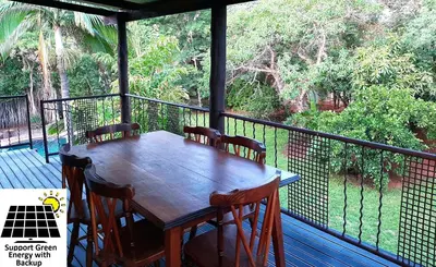 a wooden table and chairs on a deck with a view at SnL 12 Dwergarend in Malelane