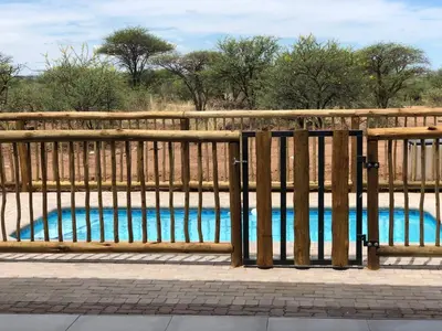a wooden fence with a swimming pool behind it at 42@ Ditholo Game Lodge in Thabazimbi