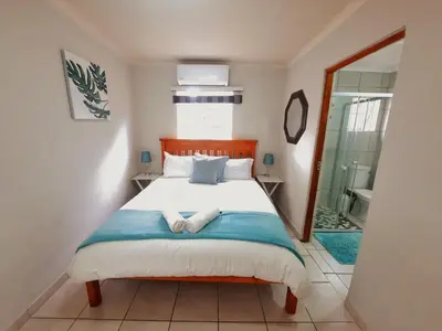 a bedroom with a bed and a glass door to a bathroom at Highlands Creek Self Catering Accommodation in Nelspruit