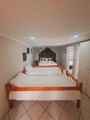 a bedroom with a large bed with white sheets at Highlands Creek Self Catering Accommodation in Nelspruit