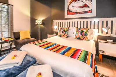 a hotel room with two beds and a couch at Hello Sunshine Self Catering Studio Apartments in Nelspruit