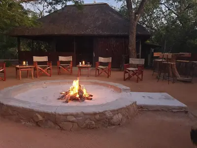 a fire pit with chairs and tables in front of a building at Kelora Bush Camp in Hoedspruit