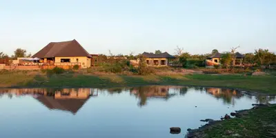 a group of houses next to a body of water at Thabamati Luxury Tented Camp in Timbavati Game Reserve
