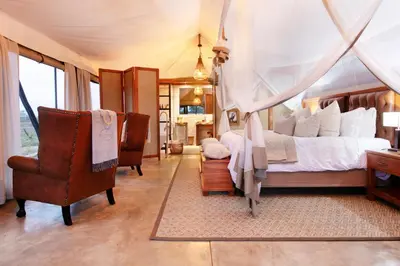 a bedroom with a bed and a desk and chairs at Thabamati Luxury Tented Camp in Timbavati Game Reserve