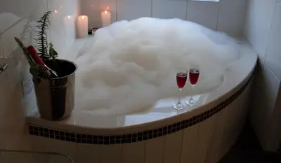 a bathtub covered in foam with wine glasses in it at Club Cocomo in Hartbeespoort