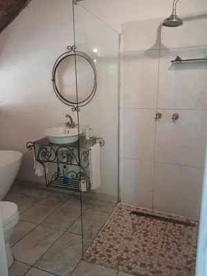 a bathroom with a shower and a sink and a mirror at Cozy Kosmos in Hartbeespoort