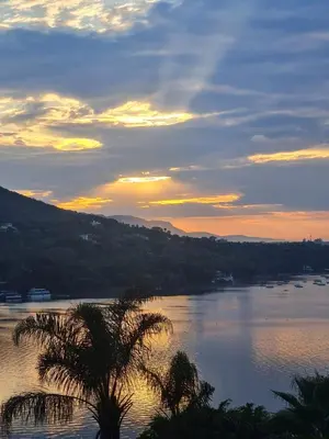a sunset over a river with a palm tree at Cozy Kosmos in Hartbeespoort