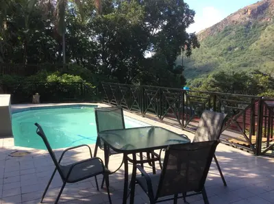 a table and chairs next to a swimming pool at Cozy Kosmos in Hartbeespoort