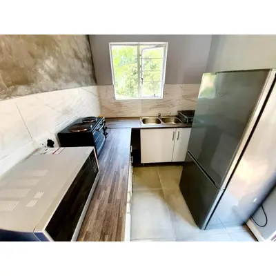 a small kitchen with a refrigerator and a sink at Waterfall Bed & Breakfast in Midrand