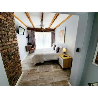 a bedroom with a bed and a brick wall at Waterfall Bed & Breakfast in Midrand