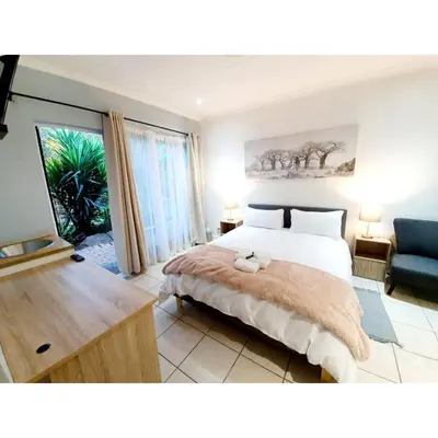a bedroom with a bed and a living room with a couch at Waterfall Bed & Breakfast in Midrand