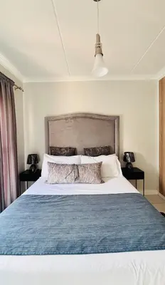 a bedroom with a large bed with a blue blanket at The Blyde Crystal lagoon Pretoria in Pretoria