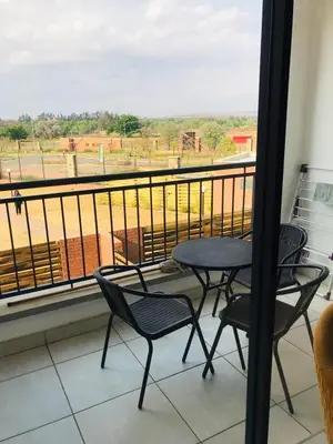 a balcony with a table and chairs and a view of a field at The Blyde Crystal lagoon Pretoria in Pretoria