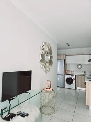 a living room with a glass table and a flat screen tv at The Blyde Crystal lagoon Pretoria in Pretoria
