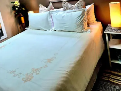 a large bed with white sheets and pillows at URlyfstyle Cottage 10km from OR Tambo Int Airport in Kempton Park
