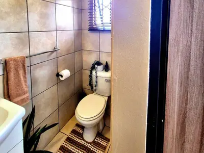 a small bathroom with a toilet and a sink at URlyfstyle Cottage 10km from OR Tambo Int Airport in Kempton Park