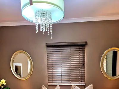 a dining room with two mirrors and a chandelier at URlyfstyle Cottage 10km from OR Tambo Int Airport in Kempton Park