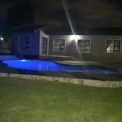 a swimming pool at night with blue lights at URlyfstyle Cottage 10km from OR Tambo Int Airport in Kempton Park