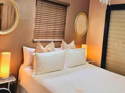 a bedroom with a bed with white sheets and pillows at URlyfstyle Cottage 10km from OR Tambo Int Airport in Kempton Park