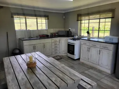 a kitchen with white cabinets and a wooden table at Mountain View Farm Cottage 4X4 Vehicles ONLY in Dullstroom