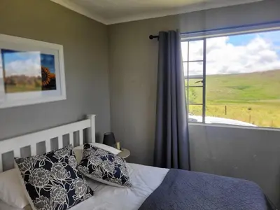 a bedroom with a bed with pillows and a window at Mountain View Farm Cottage 4X4 Vehicles ONLY in Dullstroom