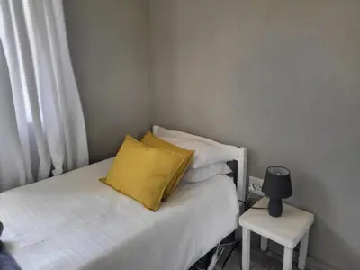 a bed with a yellow pillow and a side table at Mountain View Farm Cottage 4X4 Vehicles ONLY in Dullstroom