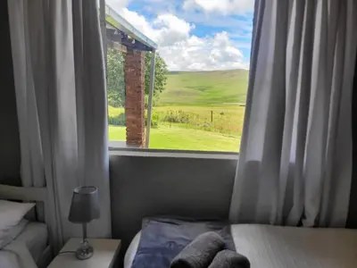 a bedroom with a window with a view of a field at Mountain View Farm Cottage 4X4 Vehicles ONLY in Dullstroom