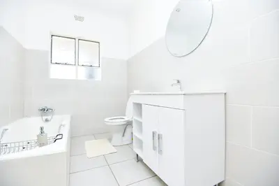 a white bathroom with a sink and a toilet at Spacious Menlyn Maine Villa in Pretoria