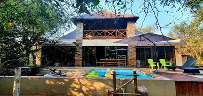 a house with a swimming pool and an umbrella at Loerie Escape - Marloth Park in Marloth Park