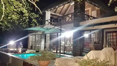 a house with a swimming pool and a blue umbrella at Loerie Escape - Marloth Park in Marloth Park