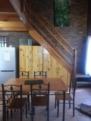 a wooden table with chairs and a staircase at Marloth Wild Fig in Marloth Park