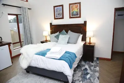 a bedroom with a bed with white sheets and blue pillows at Travetel OR Tambo Airport in Kempton Park