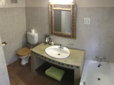 a bathroom with a sink and a toilet and a tub at Old Joe's Kaia in Schoemanskloof