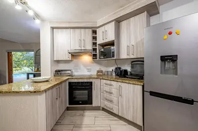 a kitchen with wooden cabinets and a stainless steel refrigerator at Kruger Park Lodge - IKZ2 - 3 Bedroom Chalet in Hazyview