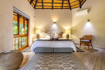 a bedroom with a bed and a chair in a room at Kruger Park Lodge - IKZ2 - 3 Bedroom Chalet in Hazyview